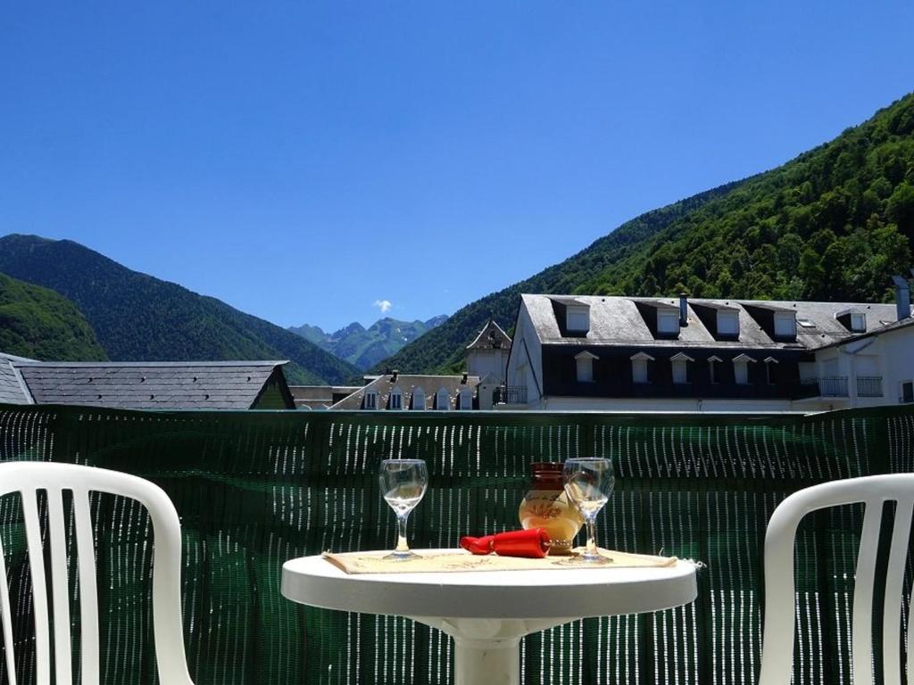 une table avec deux verres à vin sur un balcon dans l'établissement Appartement 4 pers. à Luchon - Balcons Sud, Parking et Proximité Thermes et Commerces - FR-1-313-151, à Luchon