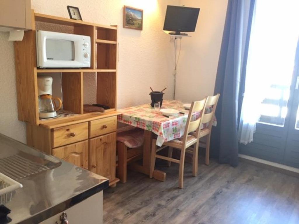 une cuisine avec une table avec des chaises et un micro-ondes dans l'établissement Studio calme pour 4 pers. à Risoul, proche pistes, animaux admis, parking gratuit - FR-1-330-512, à Risoul