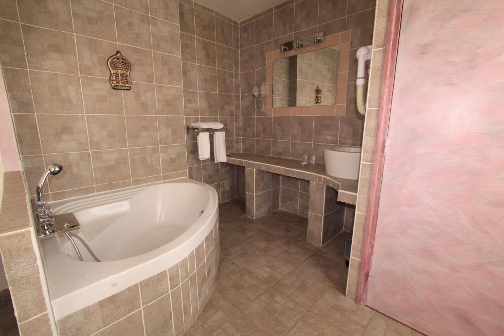 a bathroom with a bath tub and a sink at Hotel Le 5 in Martigues
