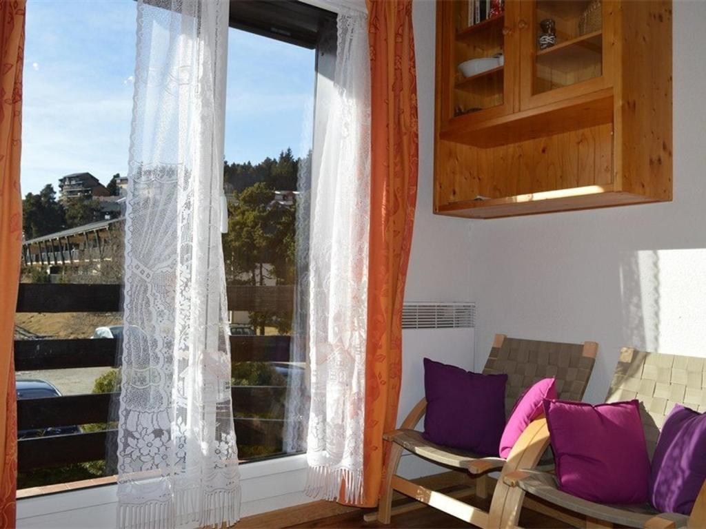 Cette chambre dispose d'une fenêtre avec des oreillers violets et blancs. dans l'établissement Studio Cabine Cosy Proche des Pistes - Sud-Ouest, Équipé pour 3 Pers., Animaux Acceptés - FR-1-592-25, à Bolquère-Pyrénées 2000