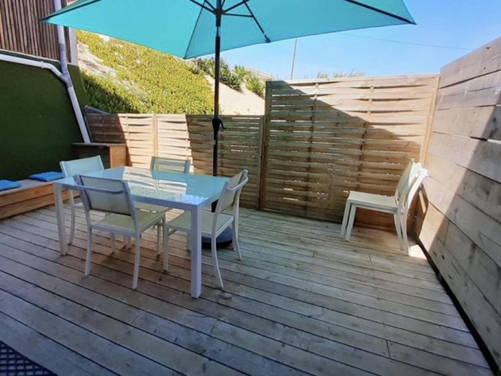 un patio avec une table, des chaises et un parasol dans l'établissement Charmant T2 proche océan avec terrasse, wifi et parking privé - Vieux-Boucau, 4/5 pers. - FR-1-379-132, à Vieux-Boucau-les-Bains