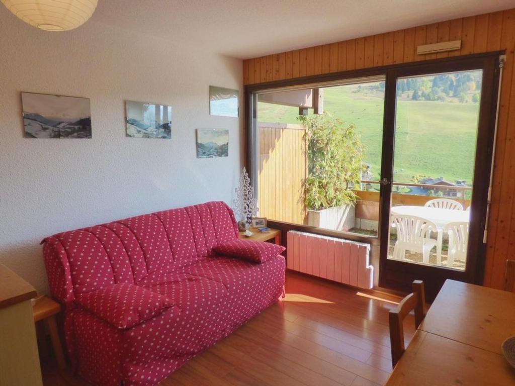 uma sala de estar com um sofá vermelho e uma mesa em Appartement Le Grand-Bornand, 3 pièces, 6 personnes - FR-1-458-93 em Le Grand-Bornand