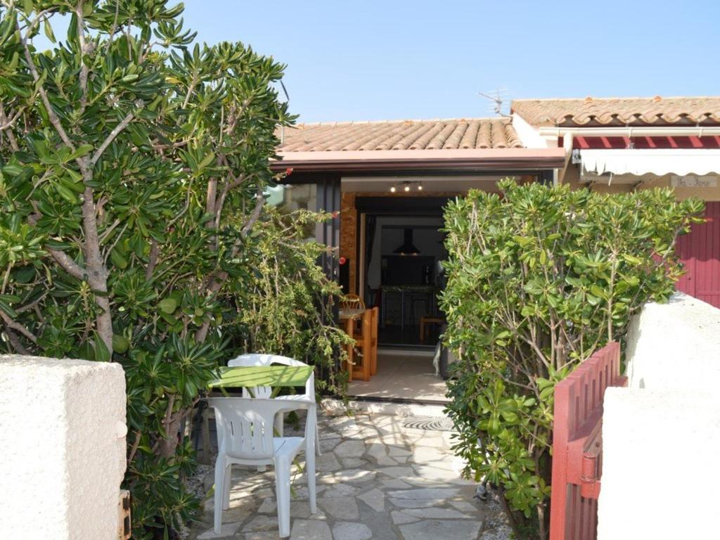 une terrasse avec deux chaises blanches devant une maison dans l'établissement Maison climatisée 2 pièces/mez, 5 couchages, proche port et plage, parking, véranda, terrasse, animaux OK - FR-1-225D-110, à Saint-Cyprien
