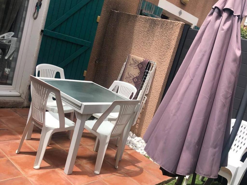 - une table et des chaises sur une terrasse avec des parasols dans l'établissement Villa T3 6 pers, Clim, Parking, Proche Mer - FR-1-81-545, à Torreilles
