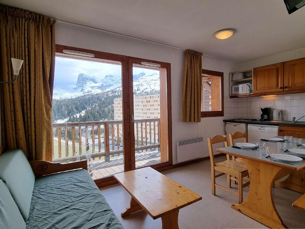 Il comprend un salon avec une table et une cuisine avec un balcon. dans l'établissement Appartement cosy 2 pièces avec balcon, proche télésiège - 6 couchages - Dévoluy - FR-1-525-197, à Saint-Étienne-en-Dévoluy
