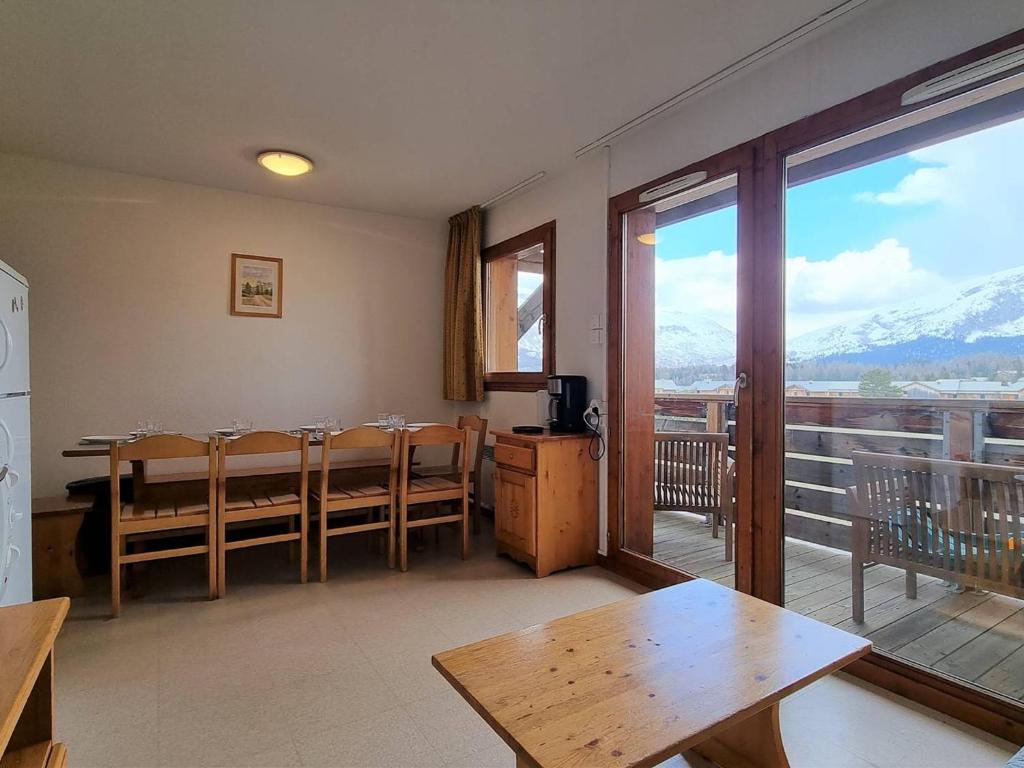 a dining room with a table and a balcony with mountains at Appartement spacieux 4 pièces avec 3 chambres, balcon, proche télésiège à SuperDévoluy - FR-1-525-201 in Le Dévoluy
