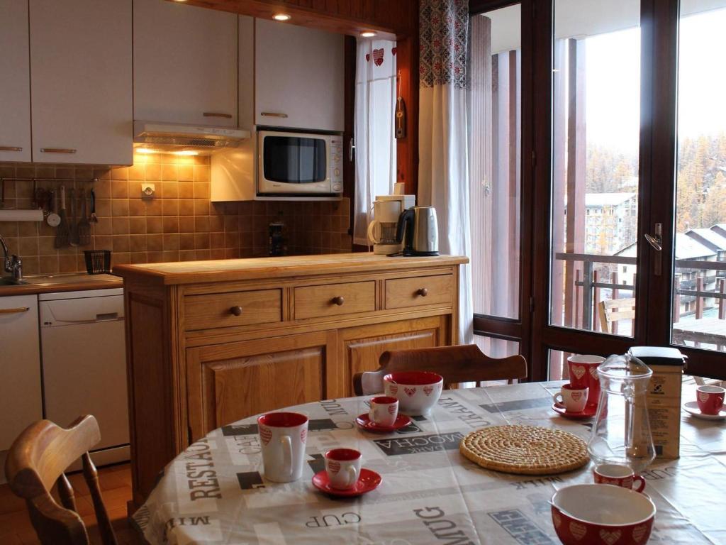 una cocina con una mesa con tazas rojas. en Appartement Vars, 1 pièce, 6 personnes - FR-1-330B-184, en Vars