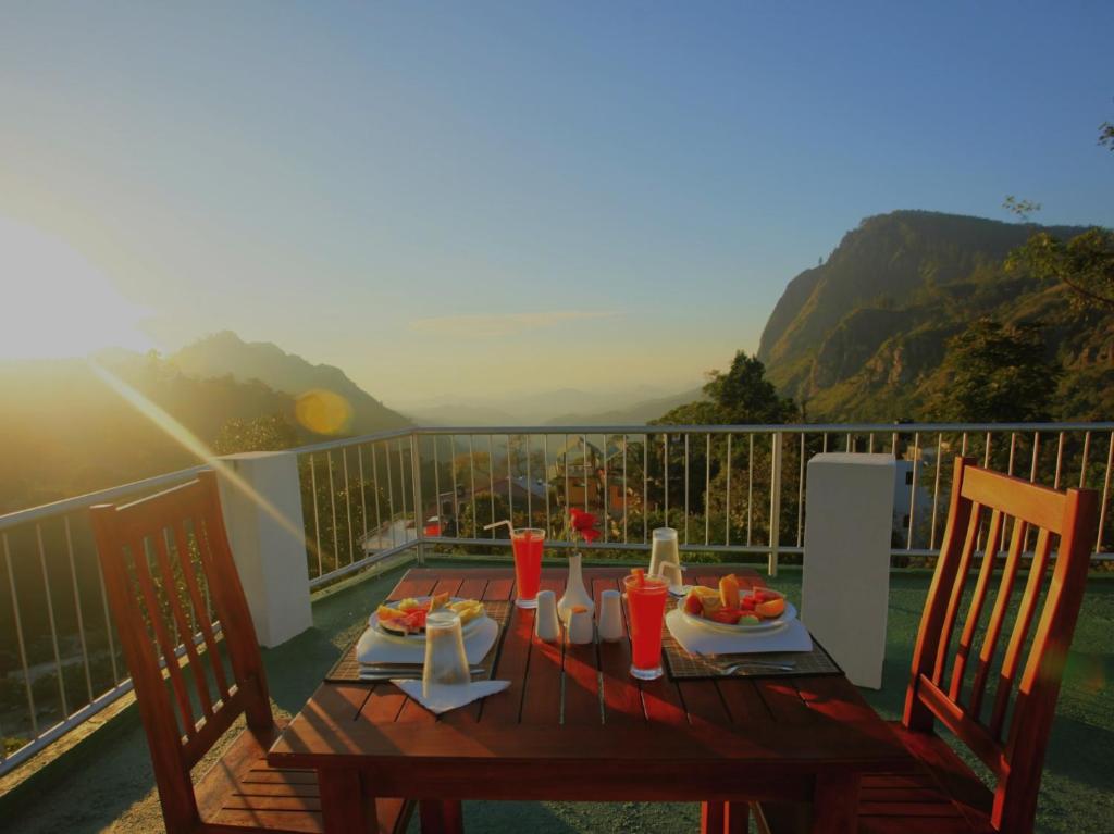 een houten tafel met eten en drinken op een balkon bij Hotel Onrock in Ella