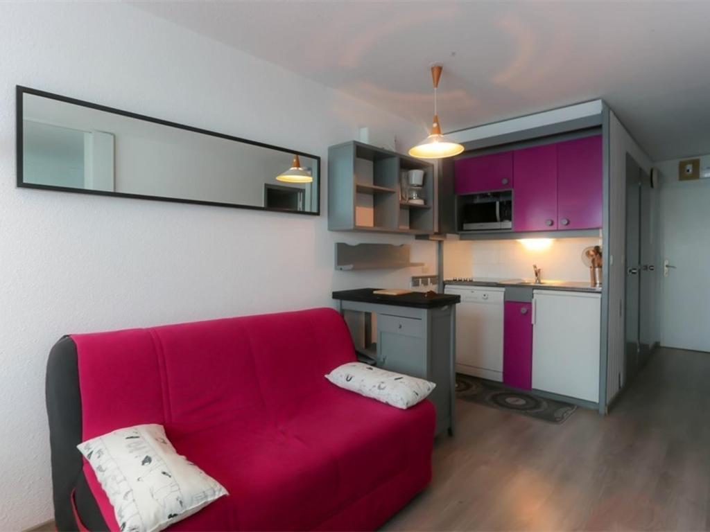 a living room with a red couch and a kitchen at Appartement Val Thorens, 3 pièces, 4 personnes - FR-1-637-22 in Val Thorens