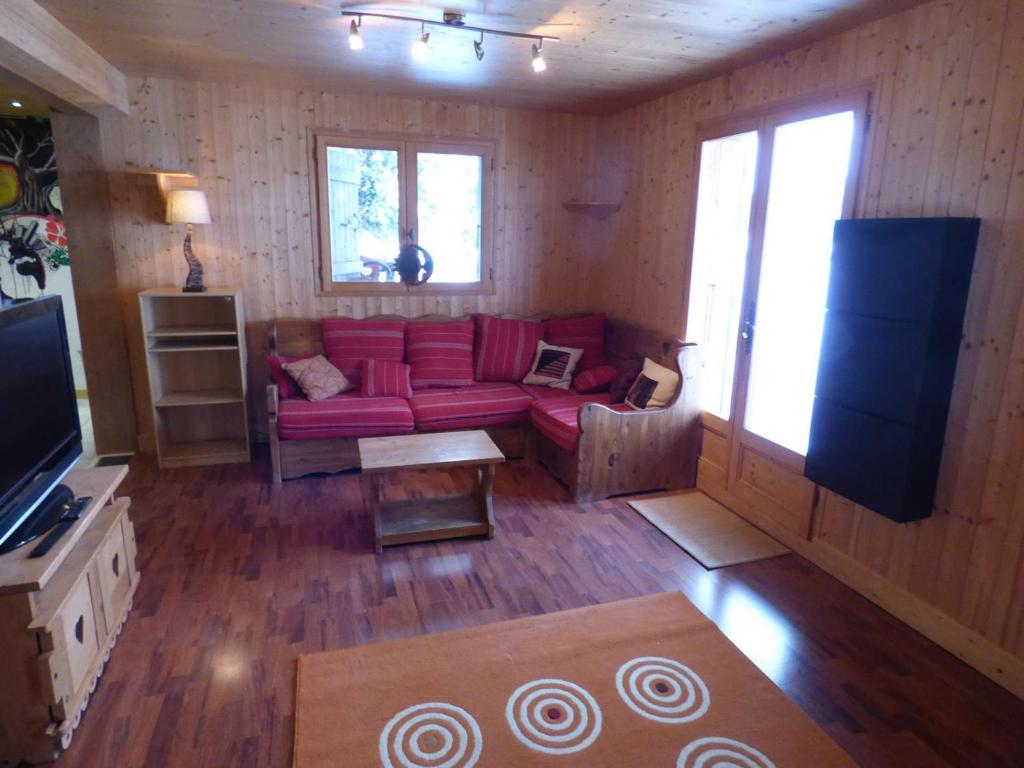 a living room with a red couch and a flat screen tv at Studio Le Grand-Bornand, 1 pièce, 2 personnes - FR-1-458-153 in Le Grand-Bornand
