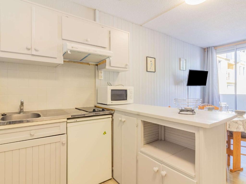 une cuisine blanche avec un évier et un micro-ondes dans l'établissement Studio cosy avec balcon, centre-ville, proche télécabine, wifi inclus - FR-1-401-235, à Cauterets