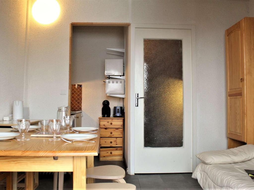 une salle à manger avec une table et une porte menant à une cuisine dans l'établissement Studio cabine au pied des pistes, 4 couchages, plein centre, balcon exposé Ouest, parking proche - FR-1-330-554, à Risoul