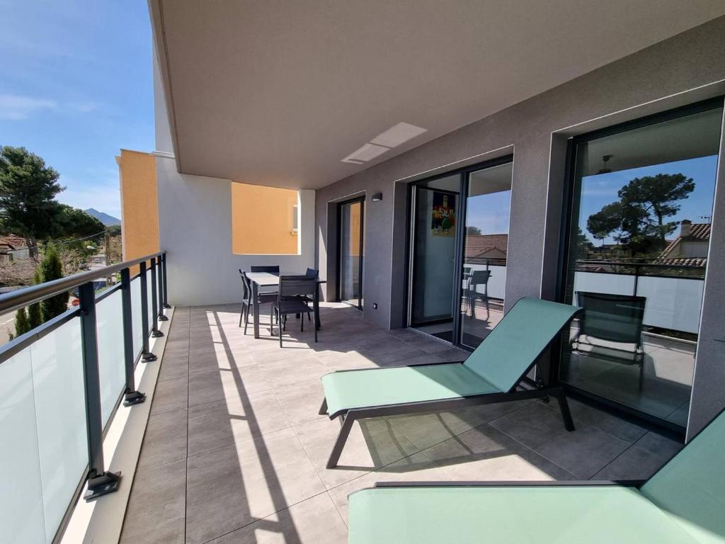 un balcon avec des chaises et des tables sur un immeuble dans l'établissement Appartement neuf climatisé, loggia spacieuse, à 200m de la mer avec parking privé - FR-1-388-206, à Argelès-sur-Mer