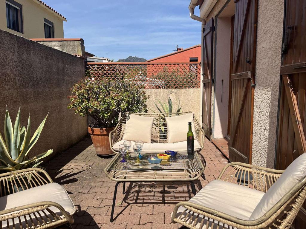 - une terrasse avec 2 chaises et une table avec une bouteille de vin dans l'établissement Maison de plain pied avec terrasse, 2 chambres, proche plage et centre-ville, climatisée et PMR - FR-1-225C-102, à Banyuls-sur-Mer