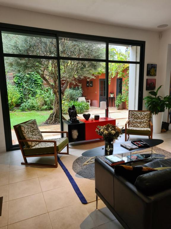 salon z kanapą i krzesłami oraz dużym oknem w obiekcie Suite indépendante avec 1 chambre et 1 bureau w Montpellier