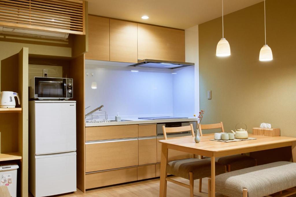 a kitchen with a table and a white refrigerator at 俪居花园酒店Reikyo Garden Hotel in Osaka