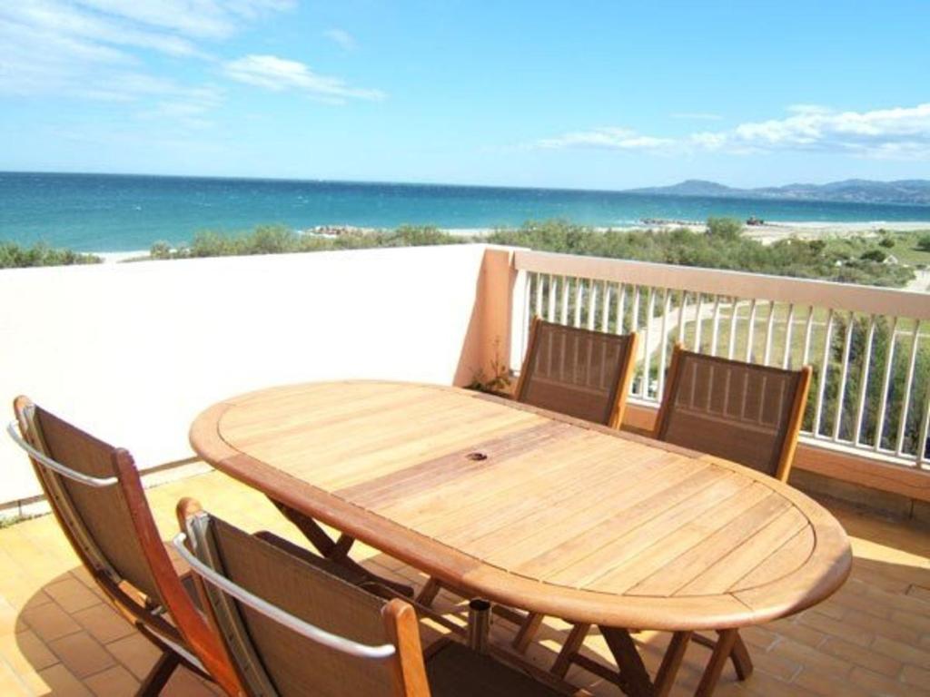 d'une table et de chaises en bois sur un balcon donnant sur l'océan. dans l'établissement Appartement 2 pièces avec parking, terrasses, animaux admis à 100m de la plage - FR-1-225D-10, à Saint Cyprien Plage