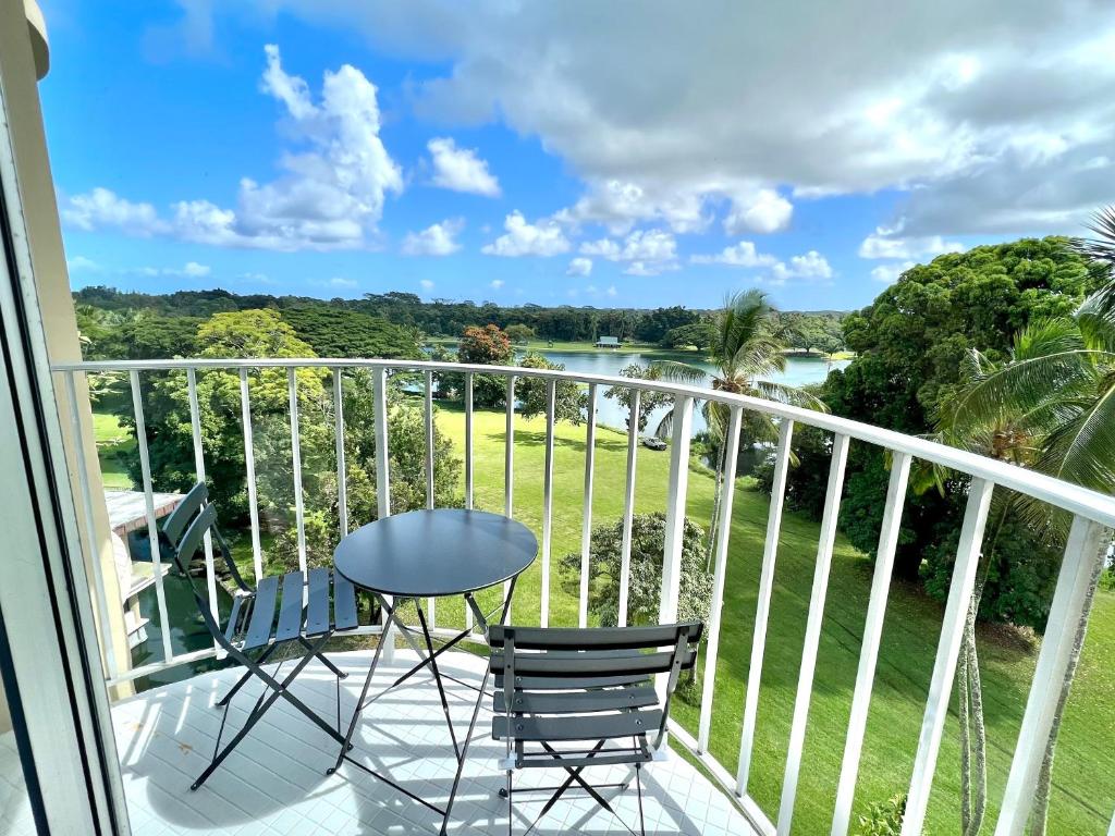 uma varanda com uma mesa e cadeiras e vista para um rio em Stunning Views Best location in Hilo 2BR modern Condo em Hilo