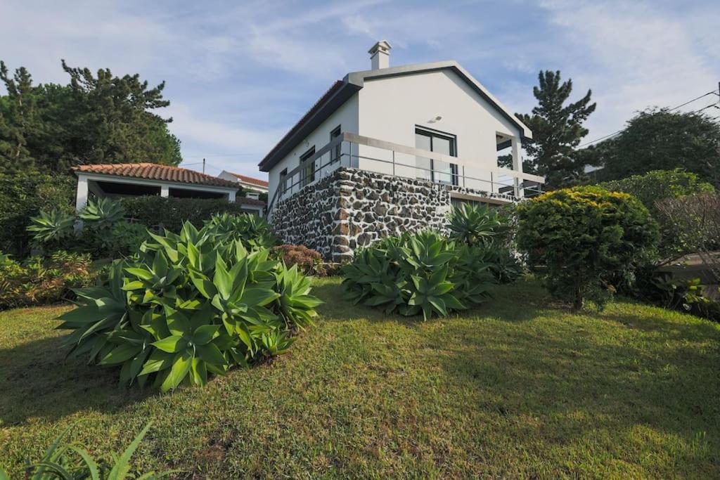 a white house with a grass yard with plants at O Nosso Refúgio in Água de Pau