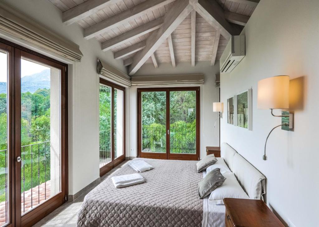 a bedroom with a large bed and large windows at Villa Elena in Menaggio