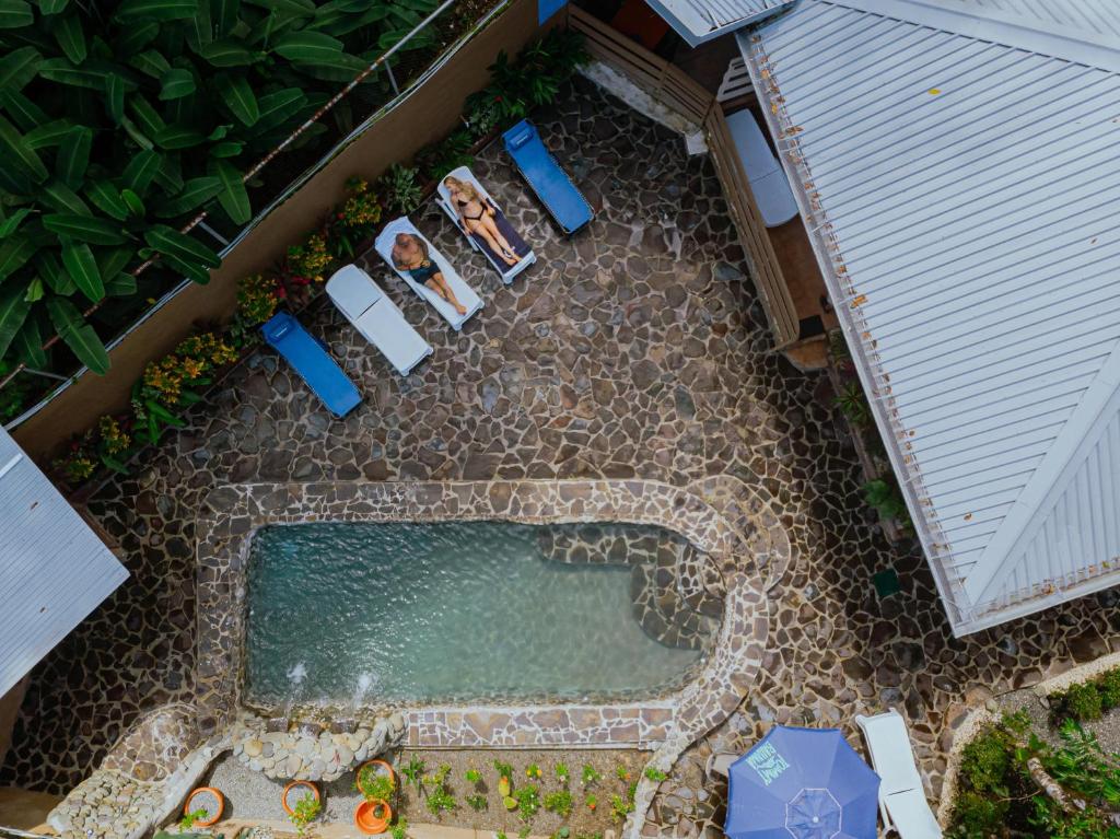 an overhead view of a swimming pool with two chairs and an umbrella at Oasis Diverse Adult Retreat in Quepos