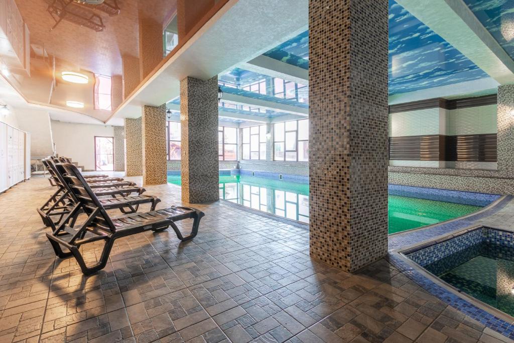 a swimming pool with two chairs in a building at Villa Vlad & Spa in Bukovel