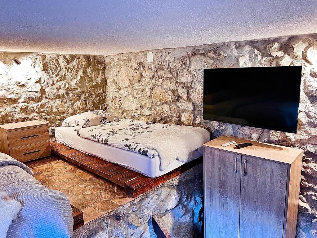 a bedroom with a bed and a flat screen tv at Stone room-Kamena soba in Šipovo