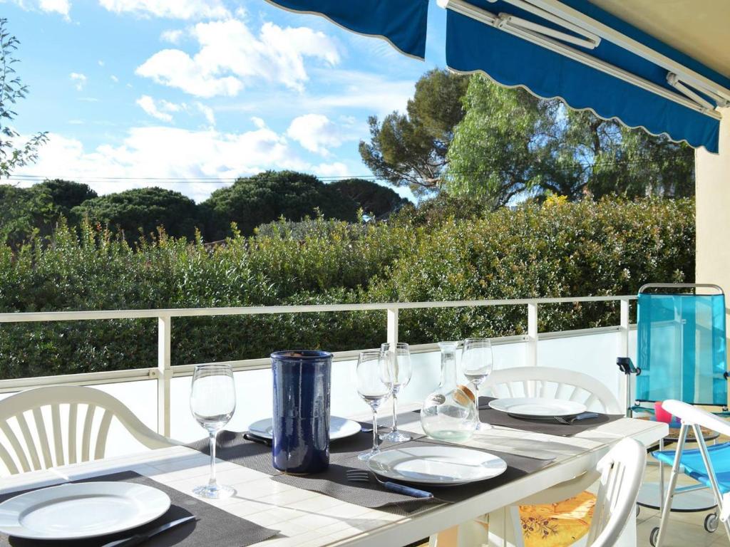 - une table avec des verres à vin et des chaises sur le balcon dans l'établissement Appartement moderne proche plage avec terrasse, parking privé - 3 pièces, 5 couchages - FR-1-251-371, à Bormes-les-Mimosas