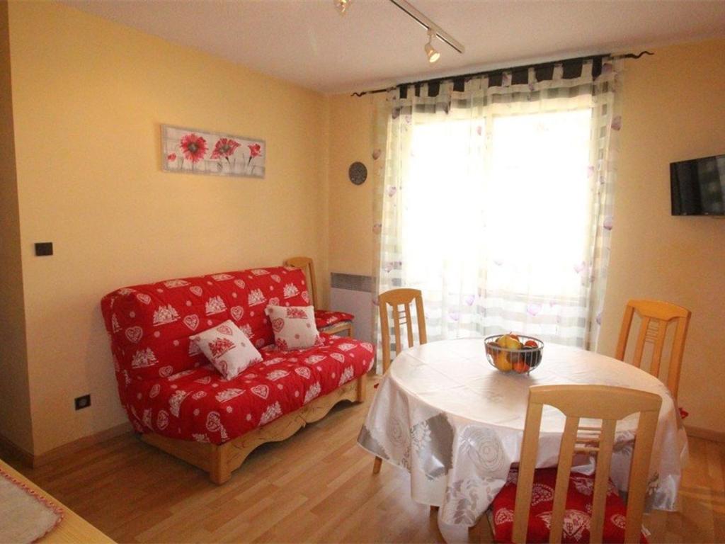 un salon avec un canapé rouge et une table dans l'établissement T2 bis au pied du télécabine, balcon, garage, centre-ville de Luchon - FR-1-313-160, à Luchon