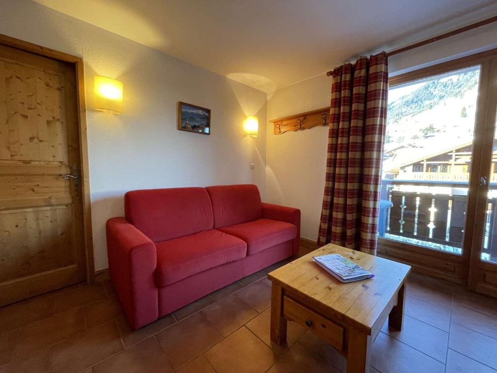 a living room with a red couch and a table at Appartement Praz-sur-Arly, 1 pièce, 4 personnes - FR-1-603-18 in Praz-sur-Arly