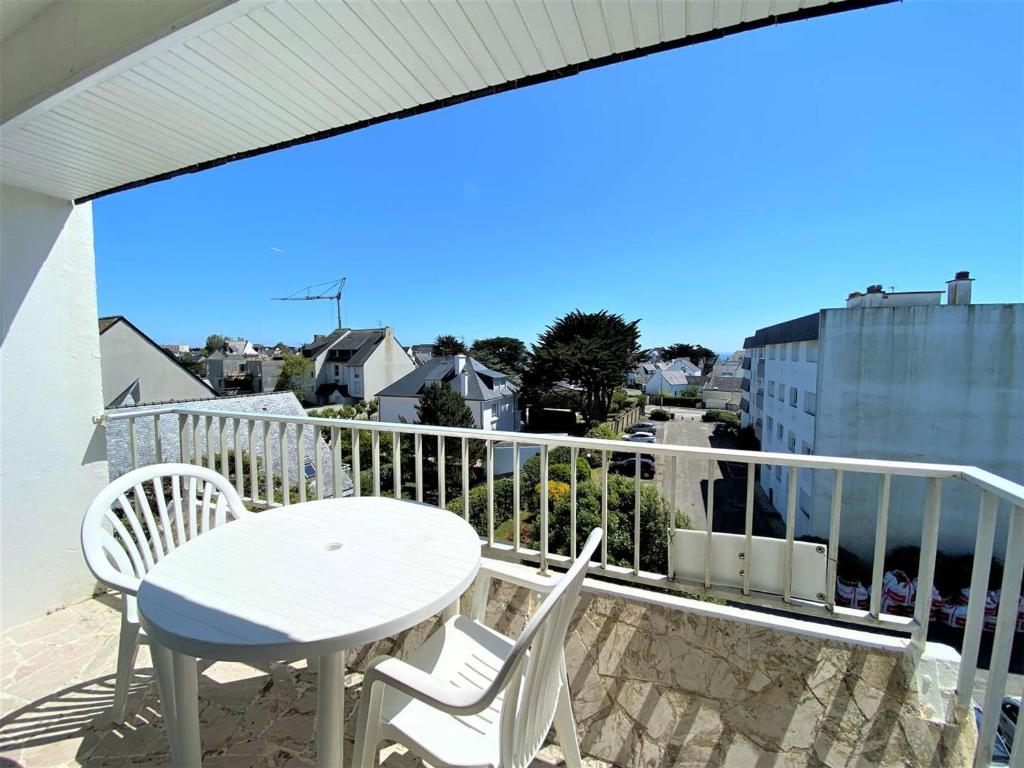 une table blanche et des chaises sur un balcon avec vue dans l'établissement Appartement 2 pièces à Quiberon - 56m², proche plage, balcon avec aperçu mer, parking inclus - FR-1-478-195, à Quiberon