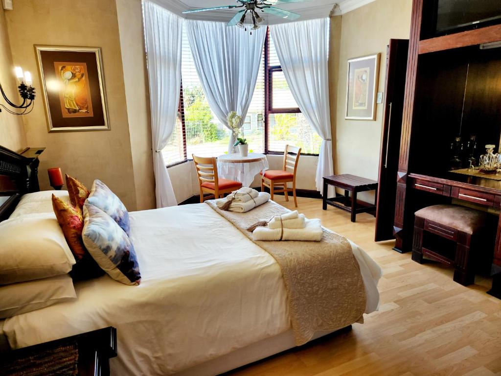 a bedroom with a large bed and a table and chairs at The Wooden Leg Guesthouse in Kleinmond