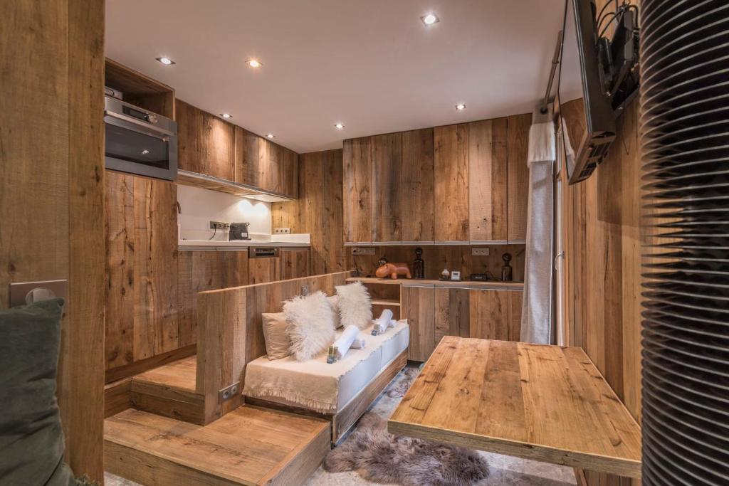 sala de estar con paredes de madera, sofá y mesa en Studio Cristallin - Welkeys en Megève