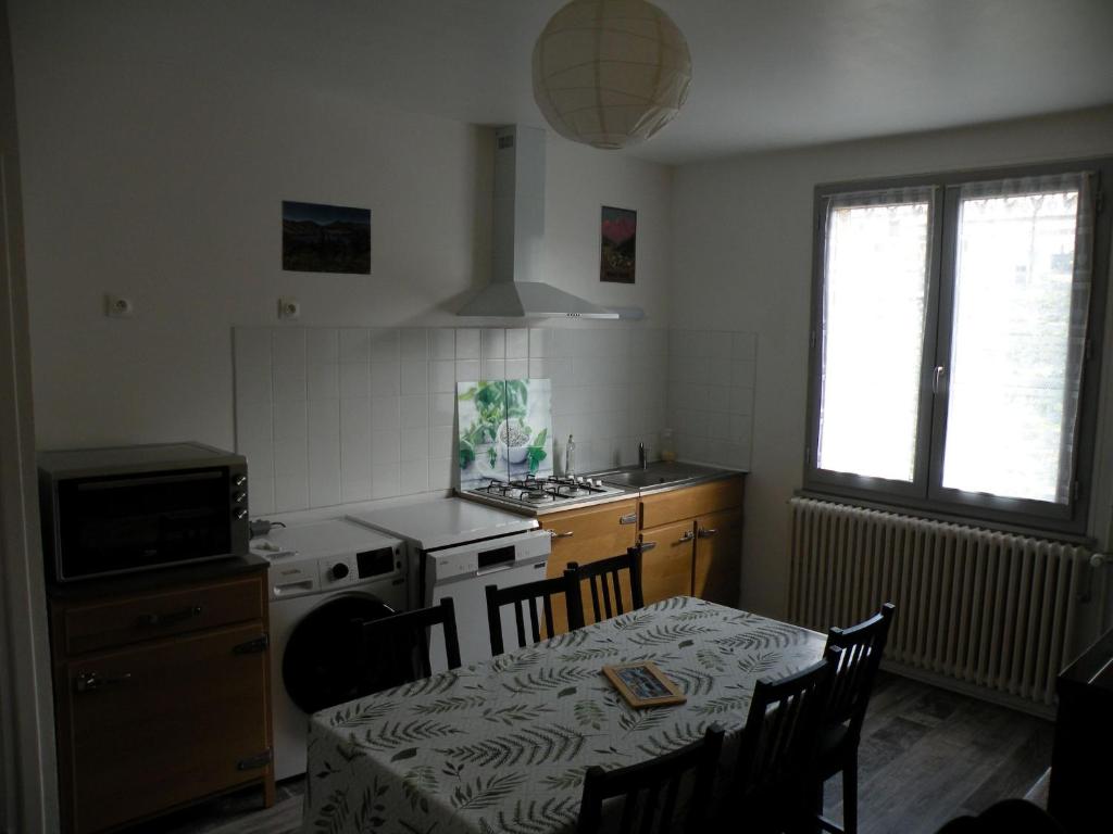 een keuken met een tafel en een fornuis top oven bij Coquelicot, Entre Volcans d Auvergne et Sancy, Orcival. in Orcival