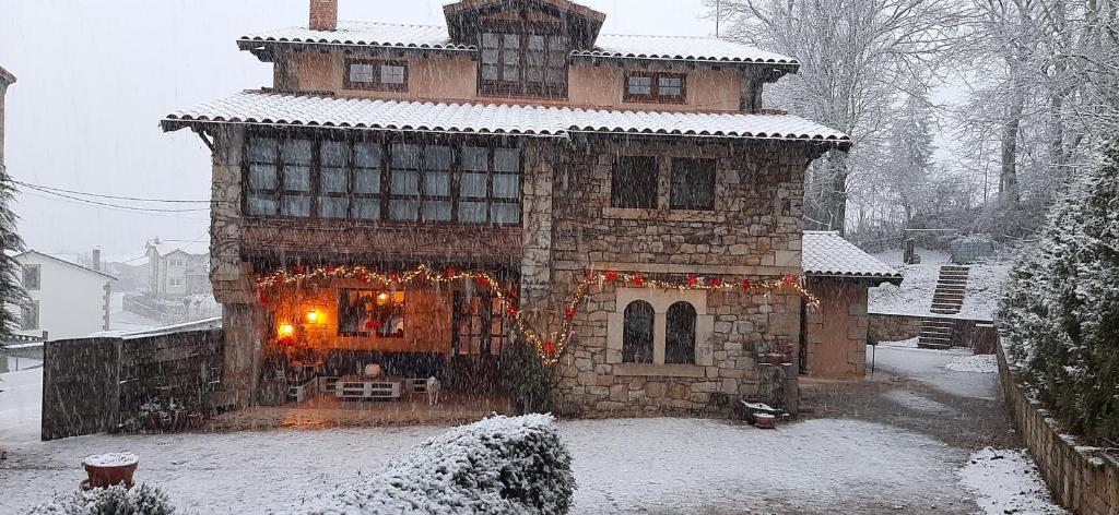 una gran casa de piedra con luces de Navidad en la nieve en La Lobera, en Las Rozas de Valdearroyo