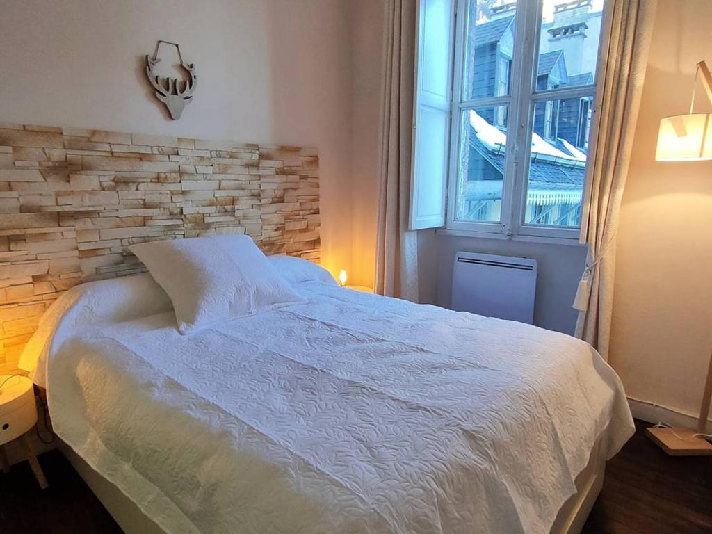 een slaapkamer met een wit bed en een bakstenen muur bij Appartement Cauterets, 2 pièces, 4 personnes - FR-1-234-271 in Cauterets