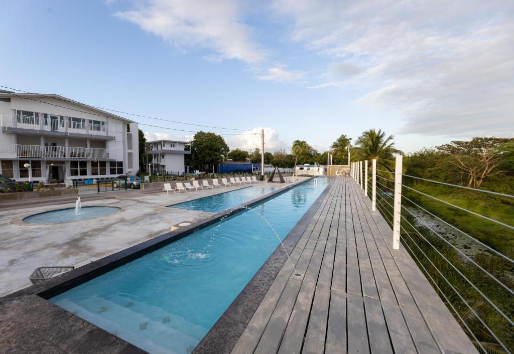 a swimming pool with a wooden deck and a building at BOHO Beach Club in Boqueron