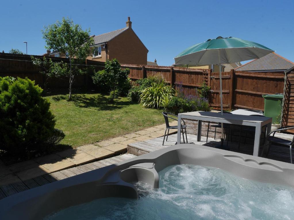 a hot tub in a backyard with a table and an umbrella at Cliffwalk Cottage in Portland