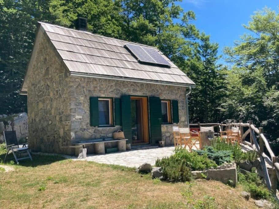 a stone cottage with a solar roof and a patio at Planinska kuća na Velebitu, s pogledom na more in Veliki Alan
