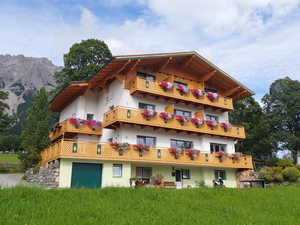 a building with balconies and flowers on it at Pension Bergpracht in Ramsau am Dachstein