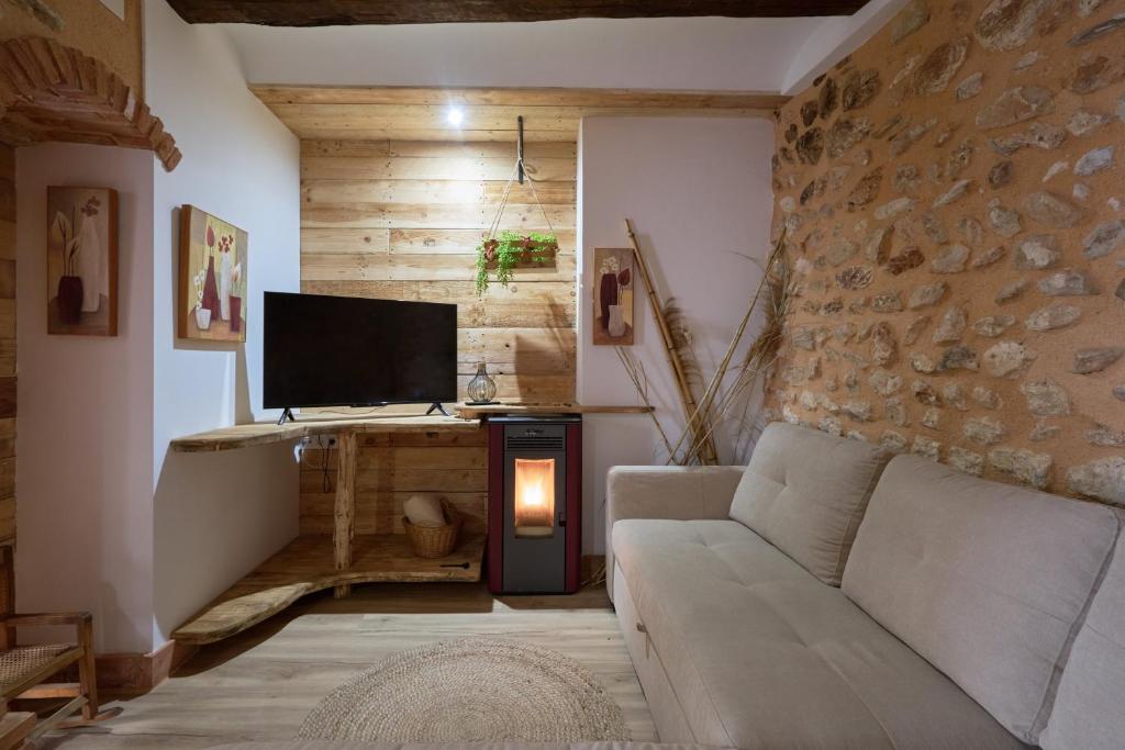ein Wohnzimmer mit einem Sofa und einem TV in der Unterkunft Ca la tía Luisa in Gayanes