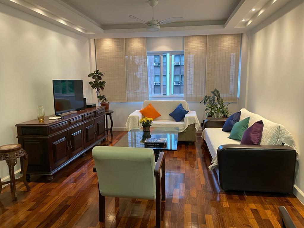 uma sala de estar com um sofá e uma televisão em Charmoso apartamento no melhor ponto de Ipanema no Rio de Janeiro