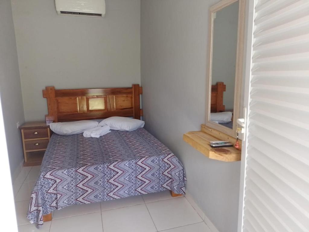 Dormitorio pequeño con cama y espejo en Pousada do Alemão - Cananéia, en Cananéia