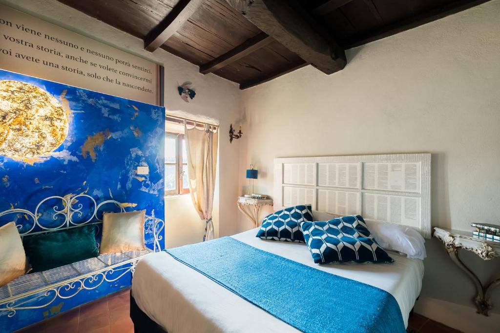 1 dormitorio azul y blanco con 1 cama con almohadas azules en Opera Suites - Le notti bianche, en Calcata