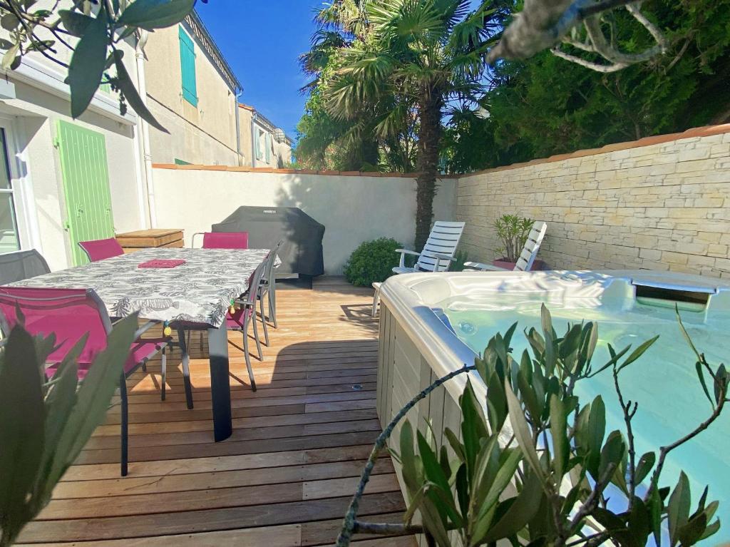 eine Terrasse mit einem Tisch und einem Pool in der Unterkunft Maison Amande in La Flotte