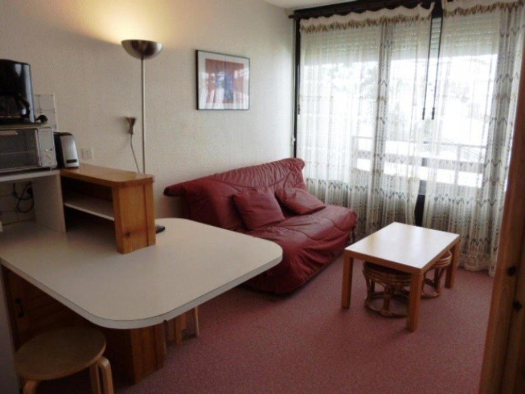 a living room with a red couch and a table at Studio Arette, 1 pièce, 4 personnes - FR-1-602-32 in Arette