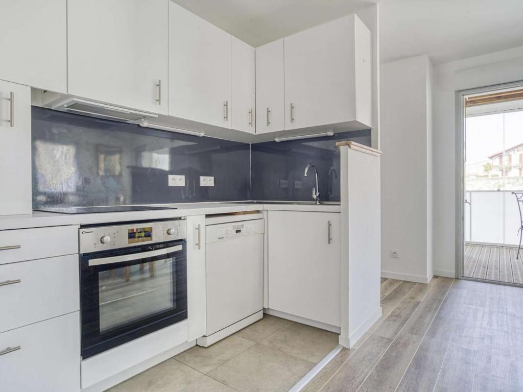 a kitchen with white cabinets and a stove top oven at Appartement Saint-Jean-de-Luz, 2 pièces, 4 personnes - FR-1-4-586 in Saint-Jean-de-Luz