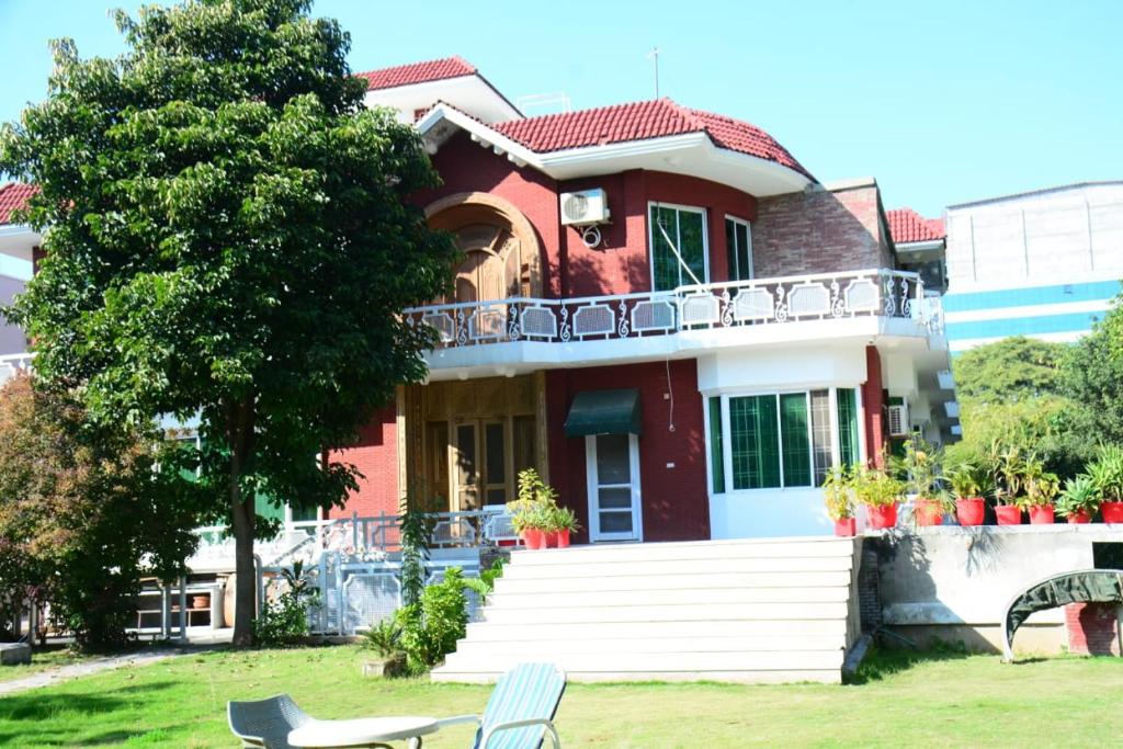 a red house with a balcony on a yard at Baani Signature in Islamabad