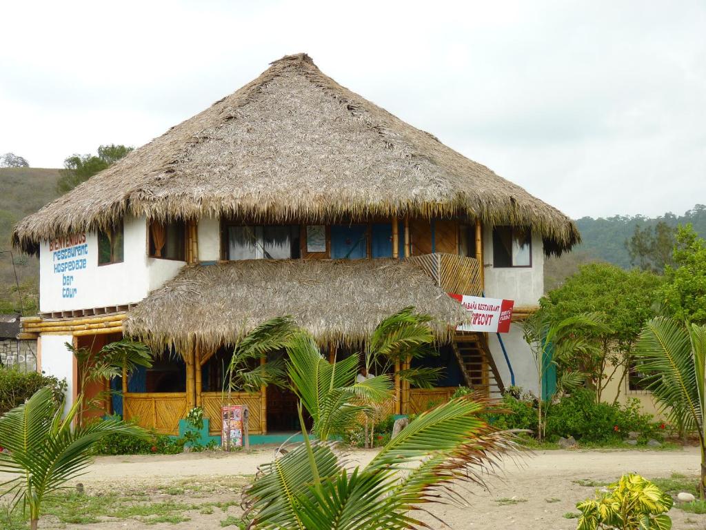 a house with a thatched roof with a sign in front at Wipeout Cabaña Restaurant in Las Tunas