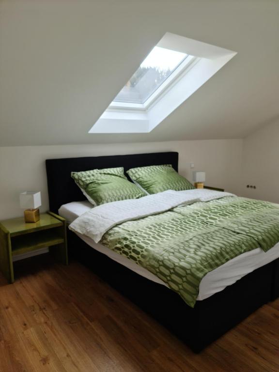 Schlafzimmer mit einem Bett mit grüner Bettwäsche und einem Fenster in der Unterkunft FederKern Simonskall in Hürtgenwald